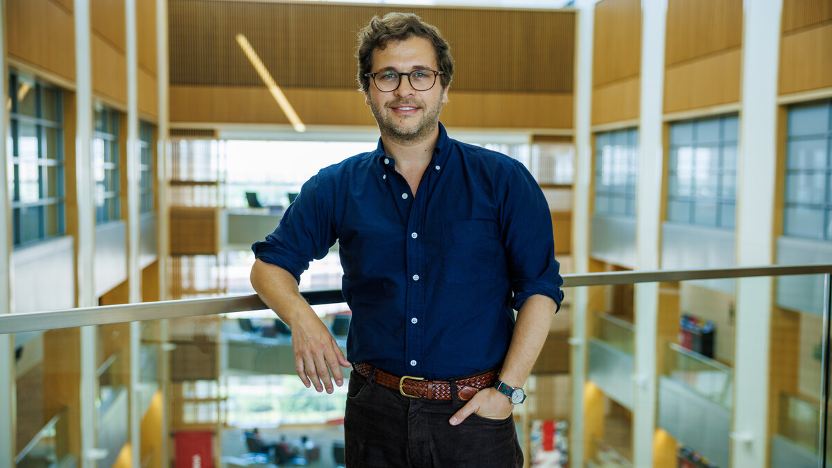 Daniel Tannenbaum, Georgia and Jim Thompson Associate Professor of Economics, stands next to a rail around the atrium to Howard L. Hawks Hall.